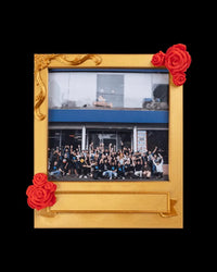 Gold-toned photo frame with red rose accents holding a group photo on a black background
