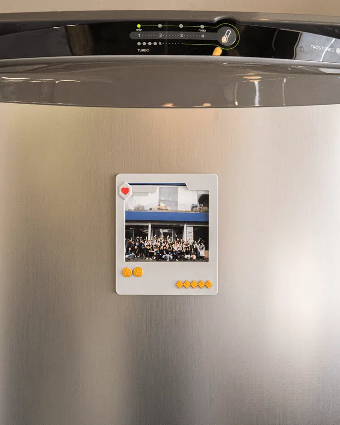 Small gray photo frame displayed on a refrigerator door