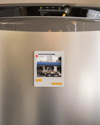 Small gray photo frame displayed on a refrigerator door