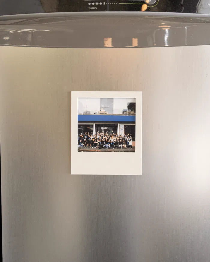 Small white photo frame displayed on a stainless steel refrigerator door