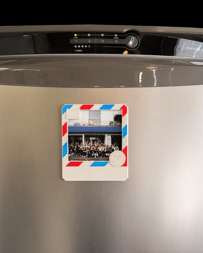 Small postcard-style photo frame displayed on a refrigerator door