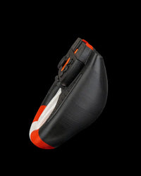 Side view of a black, white, and orange steering wheel grip holding a controller