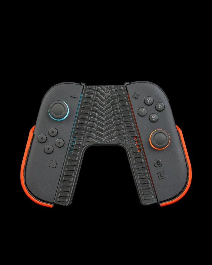 Front view of a black controller grip with orange side accents and tire tread texture