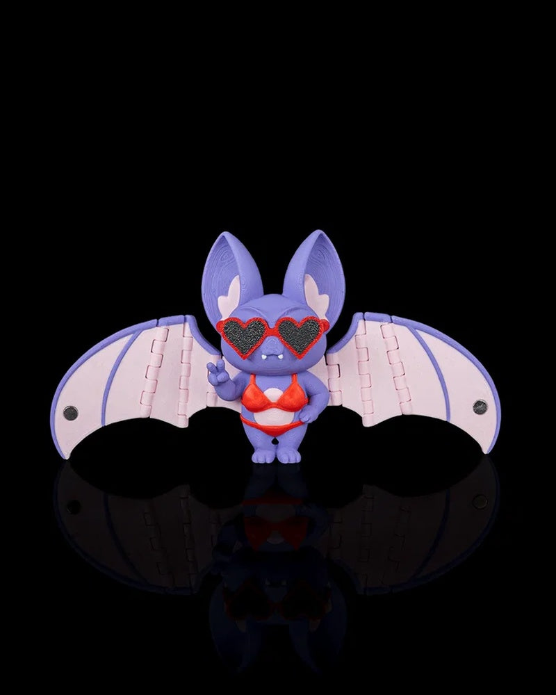 Purple bat figurine with pink wings, red swimwear, and heart-shaped sunglasses on a black background