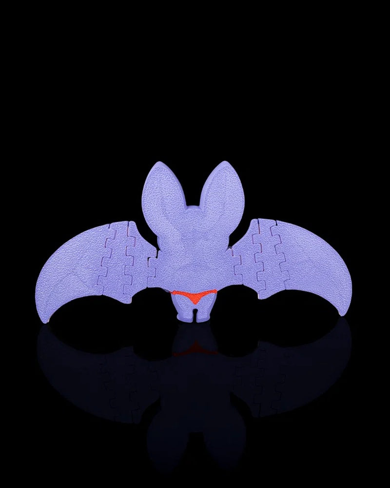 Back view of a purple bat figurine with outstretched wings on a black background