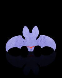 Back view of a purple bat figurine with outstretched wings on a black background