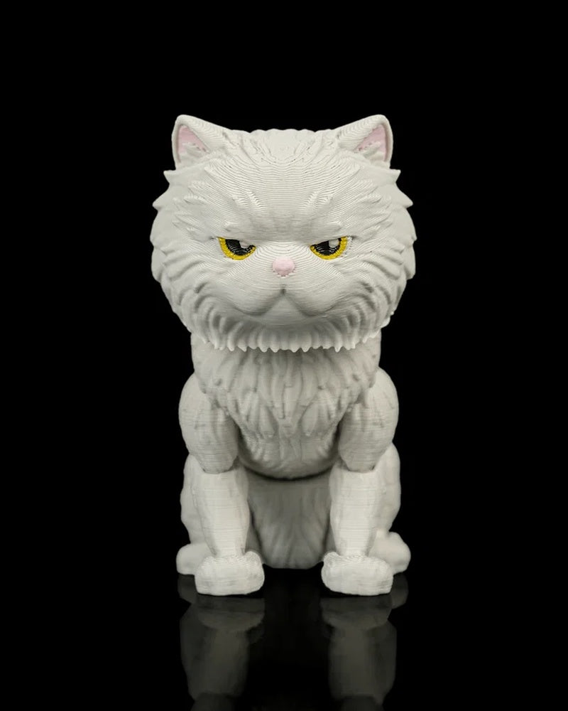 Front view of a white cat figurine with narrowed yellow eyes and a pink nose on a black reflective surface