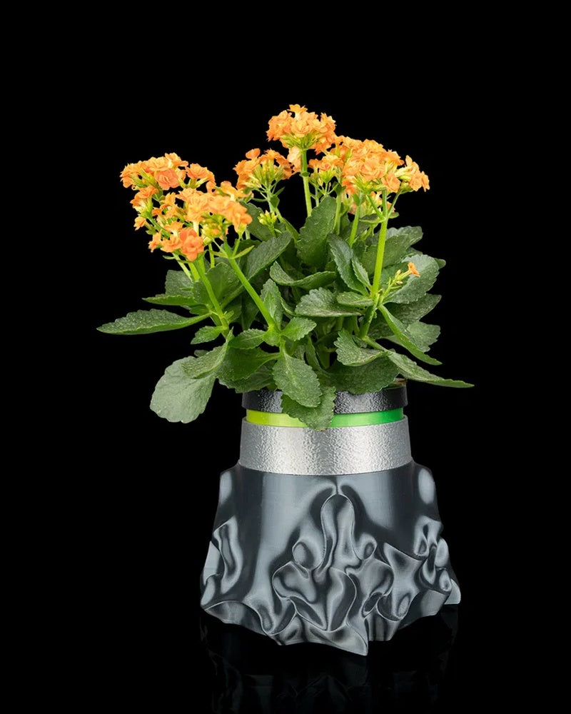 Gray sculptural planter with a green plant and orange flowers viewed from the front