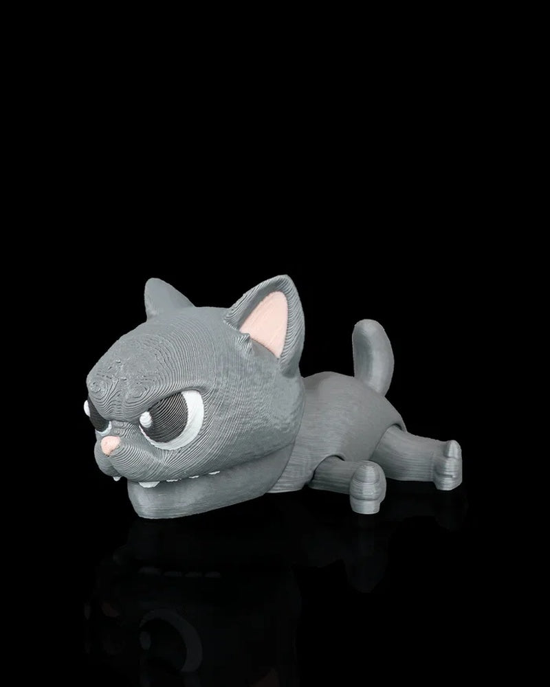 Gray cat snap toy with large eyes, pink nose, raised ears, and curled tail on a black surface