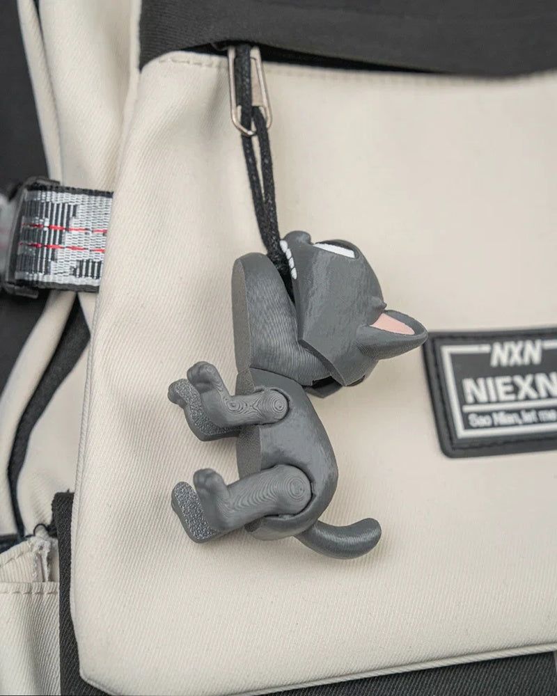 Gray cat toy hanging from a ring and cord on a beige bag