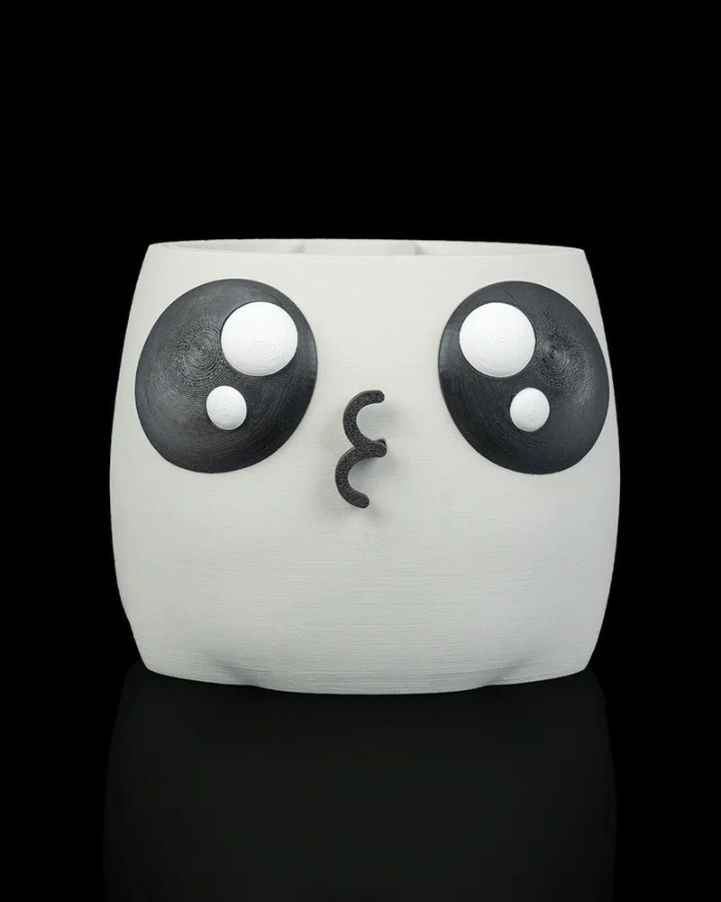 White face planter without a plant, showing large black-and-white eyes and a puckered mouth