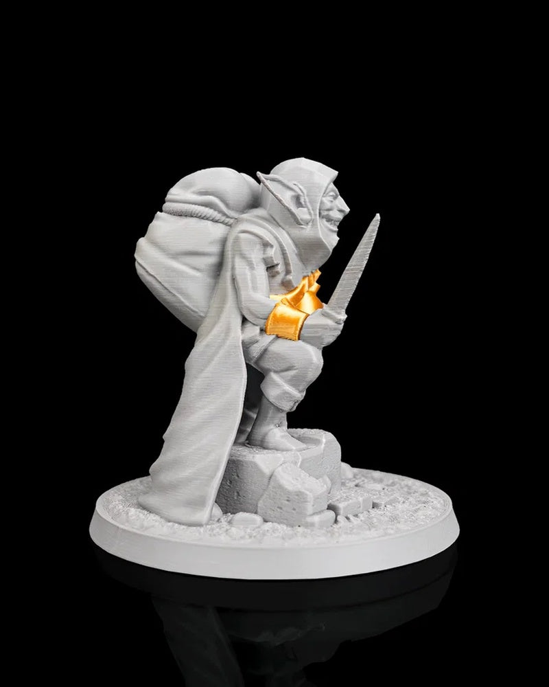 Profile view of a gray goblin figurine holding a blade with orange wrist and bomb accents on a round base
