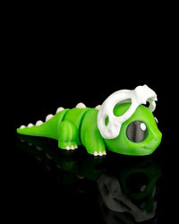 Green dinosaur figurine viewed from the side with a white skull detail over the head