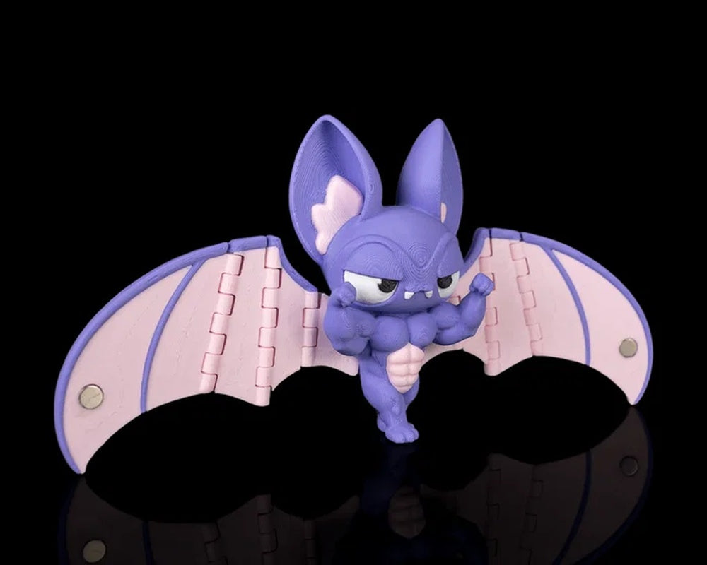 Angled view of a purple bat figurine with pink wings, large ears, fangs, and raised arm