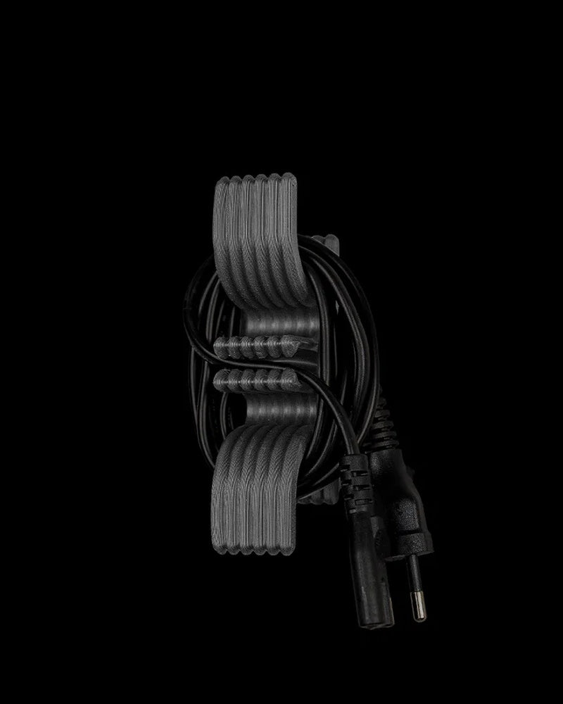 Gray ridged cord holder with a coiled black power cord on a black background