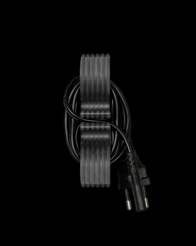 Gray ridged cord holder with a black cord looped around it on a black background
