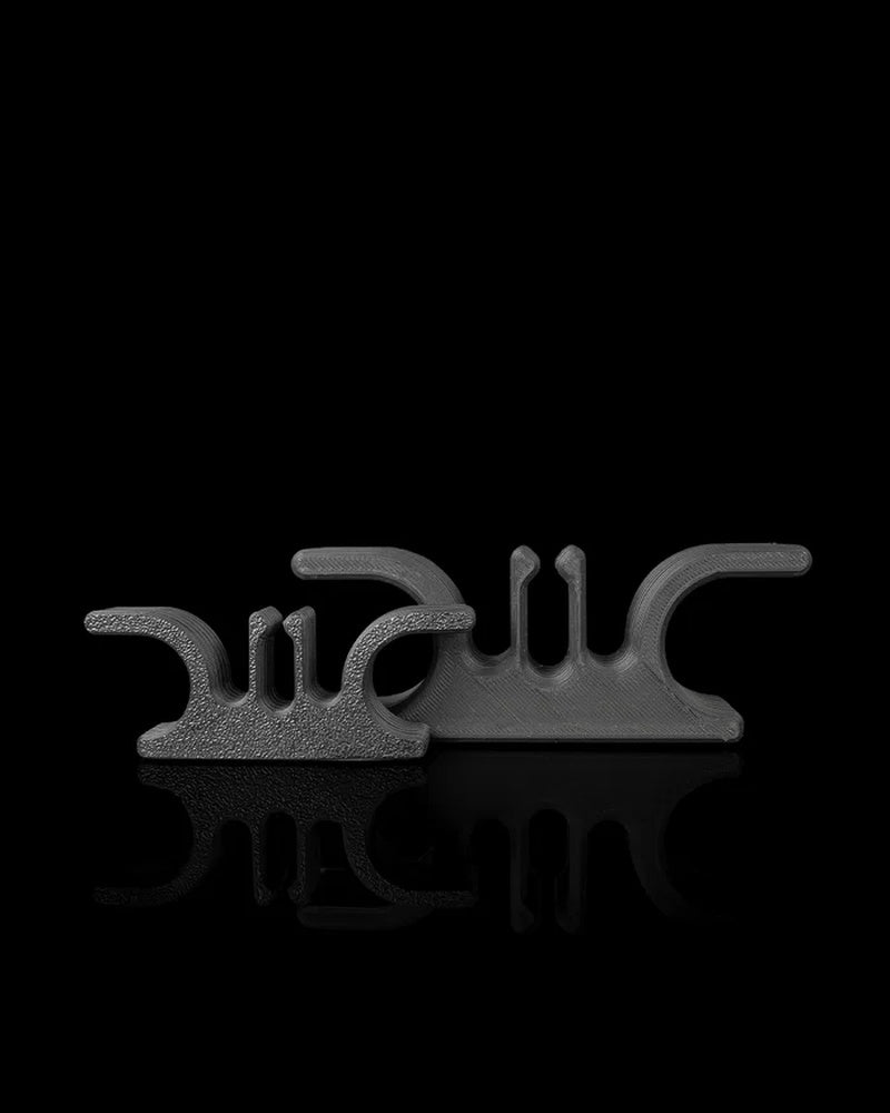 Two gray cord holders standing side by side on a black reflective surface