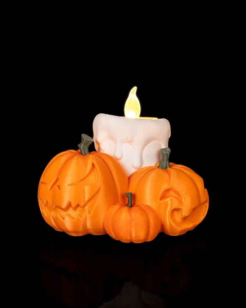 Orange pumpkin table lamp with carved faces around a white candle and glowing flame on a black background