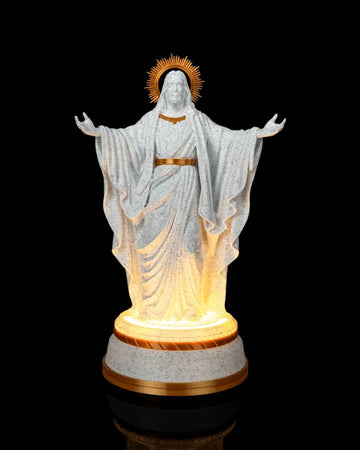 White and gold Christ statue with outstretched arms on a glowing round base against a black background