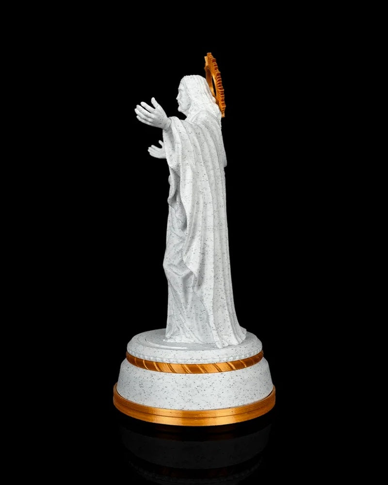 Side view of a white and gold Christ statue with draped robes and a round base