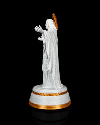 Side view of a white and gold Christ statue with draped robes and a round base
