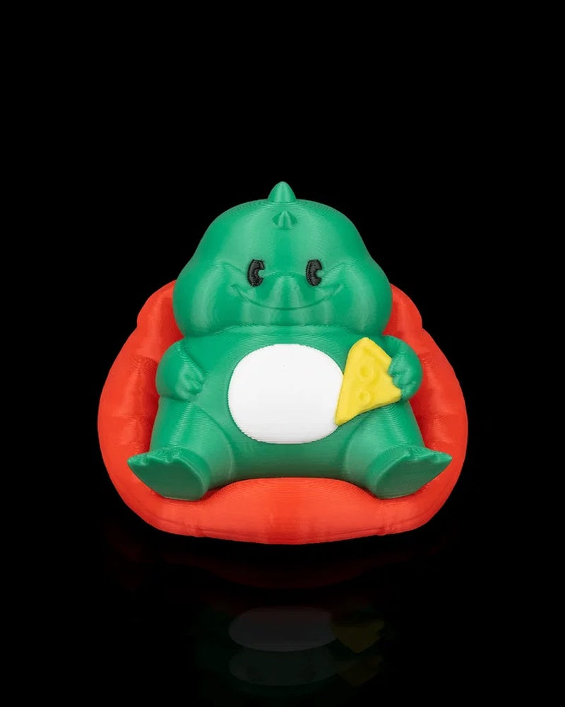 Front view of a green dinosaur figurine seated in a red chair holding a yellow triangular snack detail on a black background