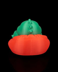 Back view of a green dinosaur figurine sitting in a red chair on a black background