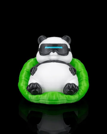 Front view of a black and white panda figurine wearing goggles while sitting in a bright green chair on a dark reflective surface.