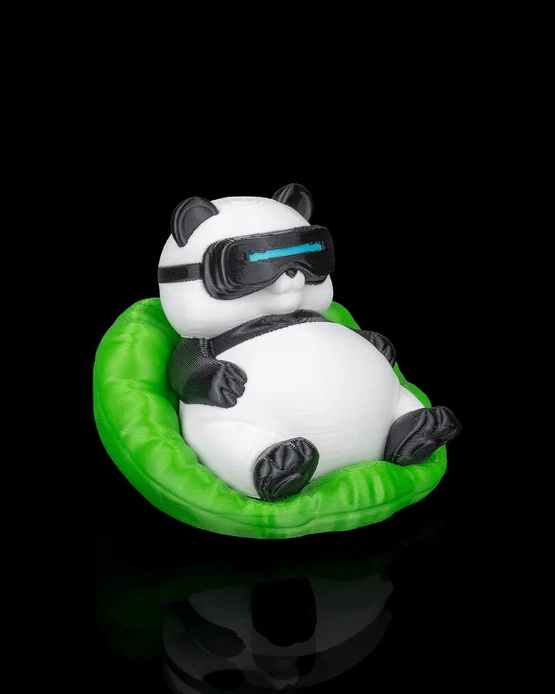 Angled front view of a panda figurine reclining in a bright green chair with black goggles and black paws.