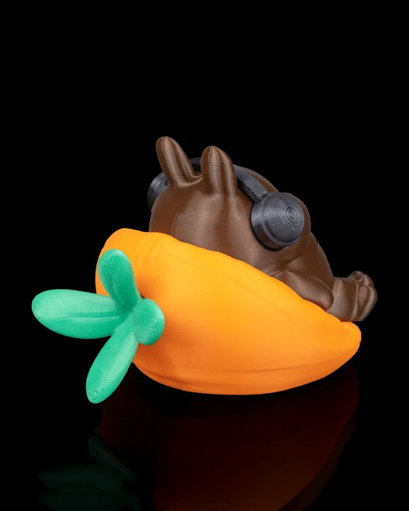 Rear angled view of a brown rabbit figurine in an orange carrot-shaped seat with green leaves and black headphones visible.