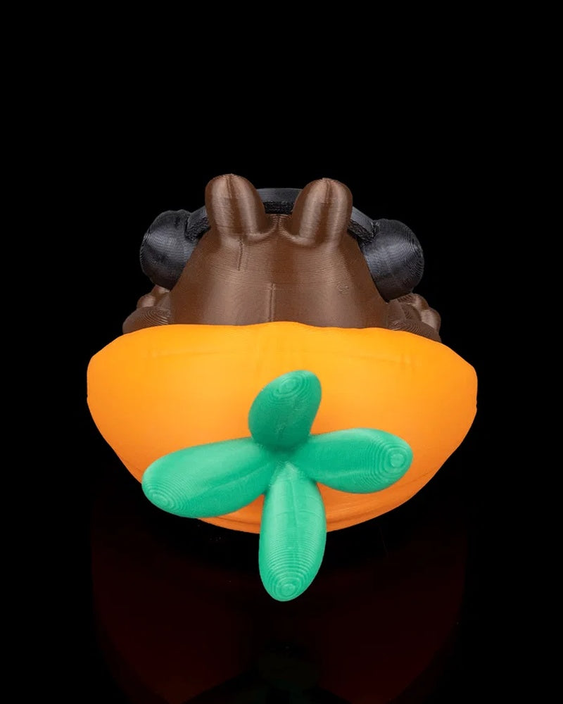 Back view of a brown rabbit figurine seated in an orange carrot-shaped form with green leaves and black headphones.