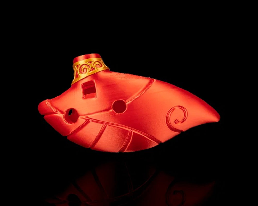 Side view of a red ocarina-shaped figurine with curved body, circular openings, and raised decorative lines