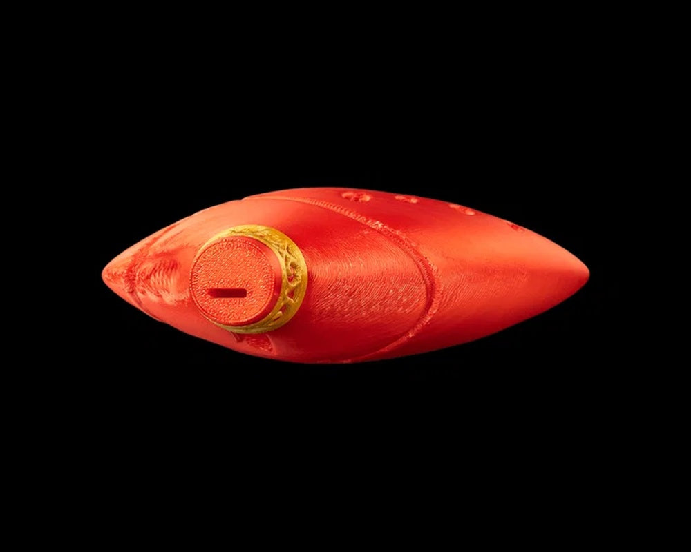 Top view of a red ocarina-shaped figurine with a gold-toned ring detail and a narrow slot