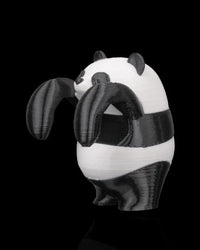 Side view of a black-and-white panda figurine with rounded body and raised paws