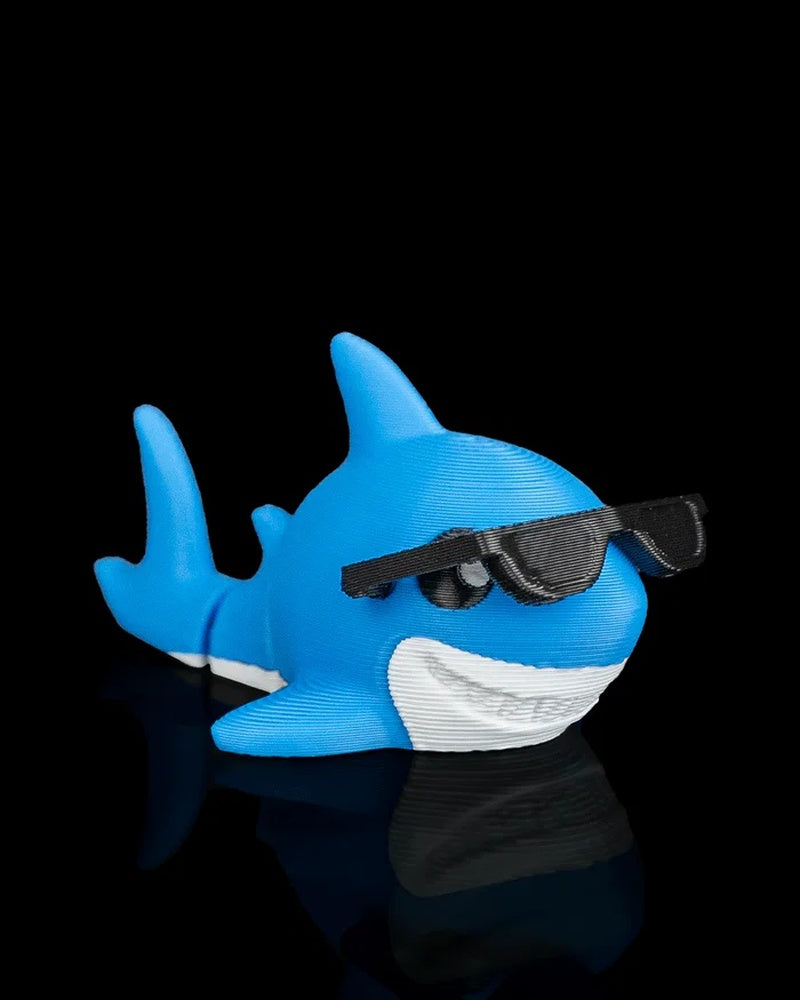 Side view of a blue shark figure with black sunglasses, a white underside, side fin, and raised tail.
