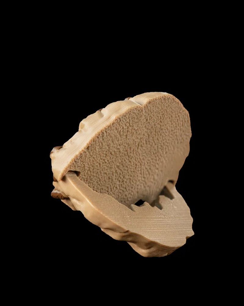 Side view of a tan round monster form opened to show the textured underside and inner mouth on a black background.