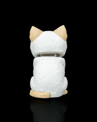 Rear view of a cream and white cat figure with tan ears and tail on a black background