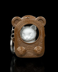 Front view of a brown bear-eared pack-shaped case with a pale cat face visible through a round opening and a metal ring at the side