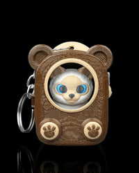 Front view of a brown bear-eared pack-shaped case with a Siamese cat face visible through a round opening and a metal ring at the side