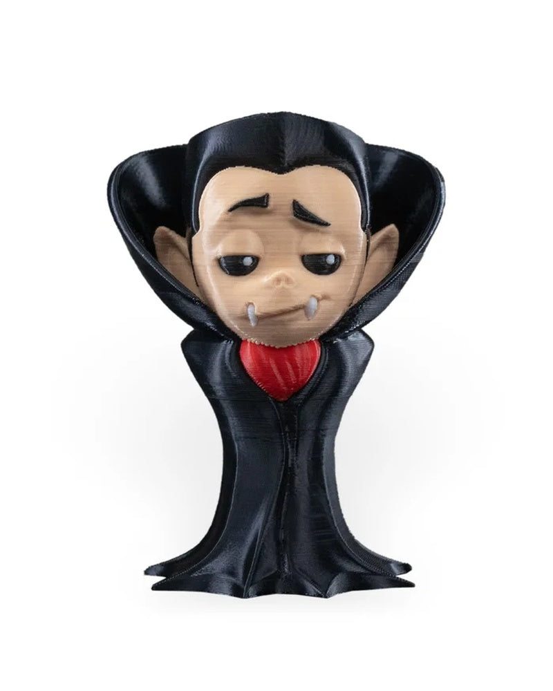Front view of a small monster figure with a black raised collar, pale face, white fangs, and red chest accent on a white background.