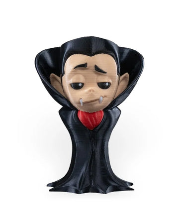 Front view of a small monster figure with a black raised collar, pale face, white fangs, and red chest accent on a white background.