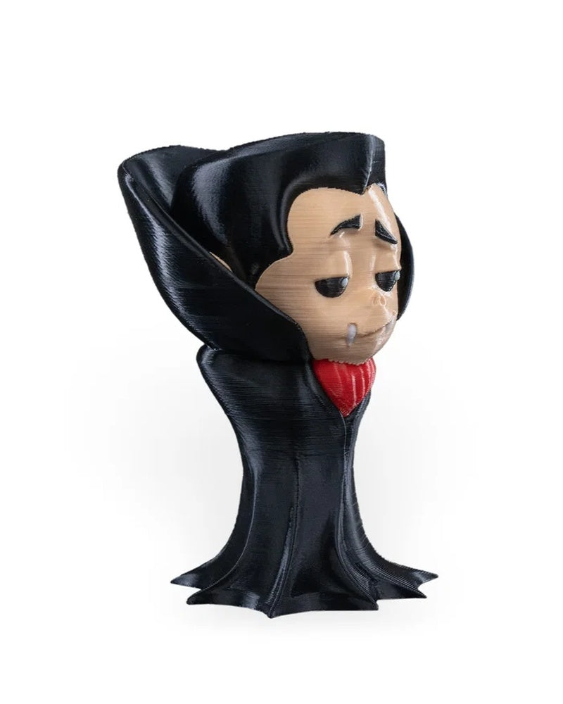 Side angled view of a small monster figure showing a pale face, black raised collar, white fangs, and red front accent.