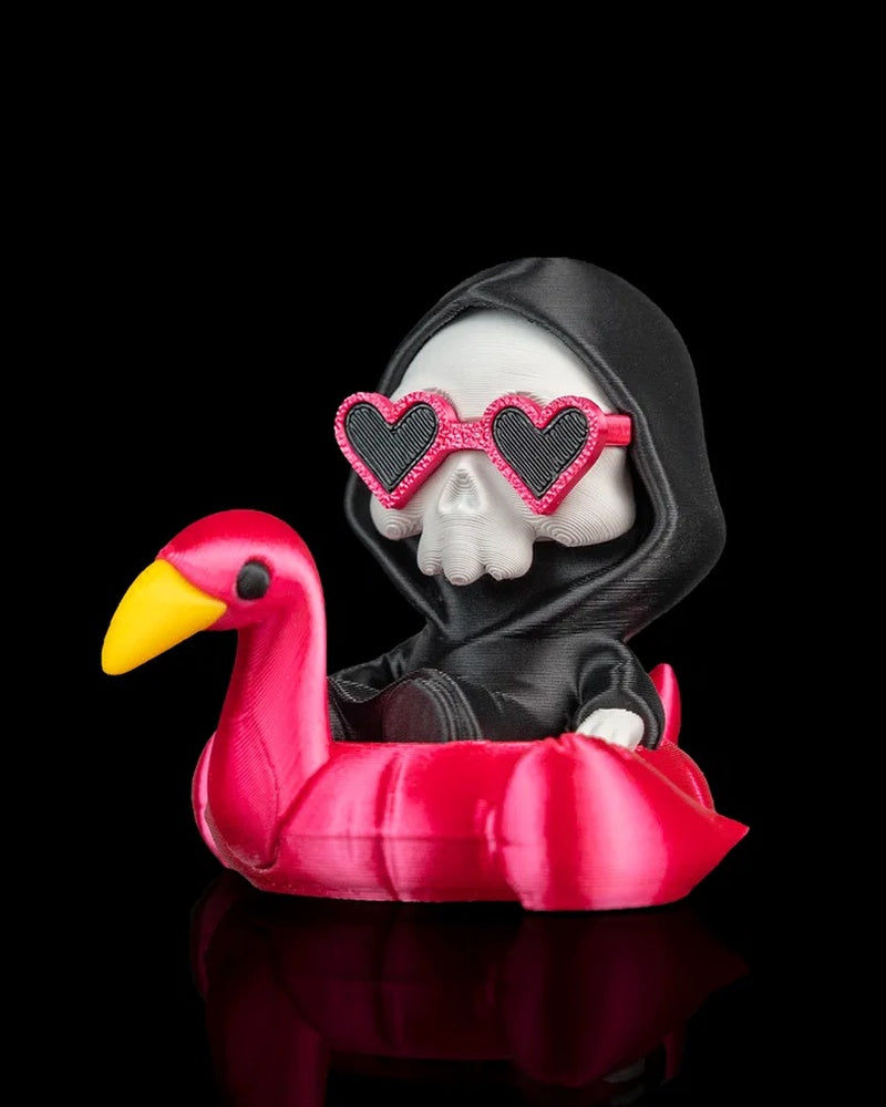 Hooded skull character wearing heart-shaped sunglasses while sitting in a pink flamingo float on a black background