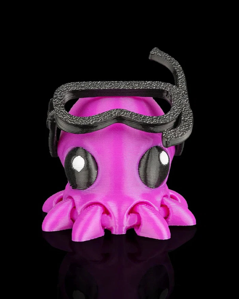 Front view of a bright pink octopus figure wearing black goggles and a snorkel on a black background.