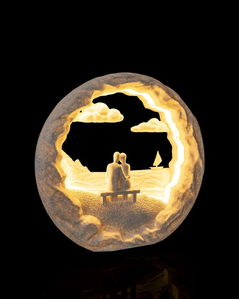 Angled view of a round illuminated seaside scene lamp with bench figures, clouds, and sailboat