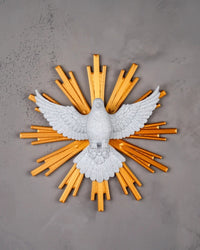 White dove figurine with golden rays mounted on a gray wall