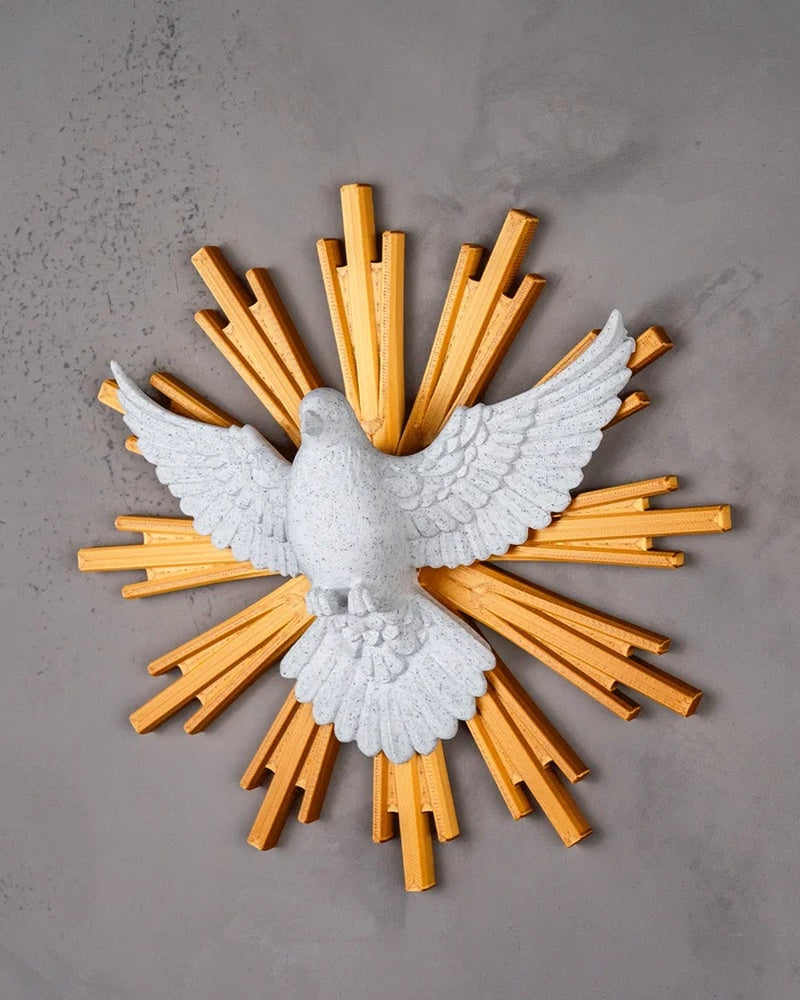 Angled view of a white dove figurine with spread wings and golden rays on a gray wall
