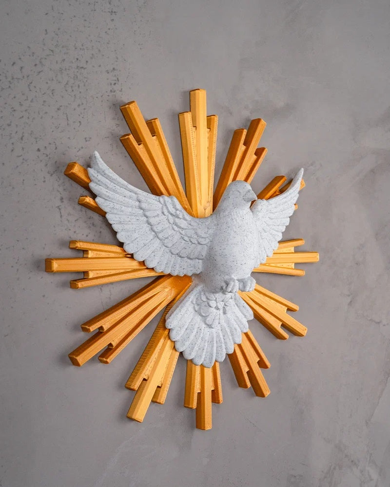 Side view of a white dove figurine with raised wings and golden rays on a gray wall