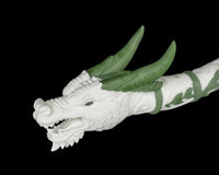 Close-up of a white dragon head with green horns and an open mouth