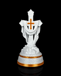 Front view of a white speckled draped cross statue with gold-tone accents on a tiered base against a black background.